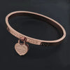 Delicate heart charm on stainless steel bangle, symbolizing love